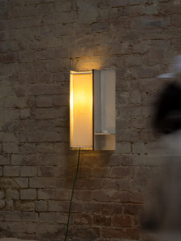 A wall lamp made of hand brushed aluminium with a strip of dark hardwood and a soft calico cover. Designed and made by Liam Barwick